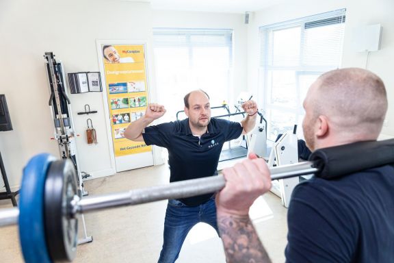 fysiotherapeut legt aan patiënt uit hoe je het beste krachttraining oefeningen doet